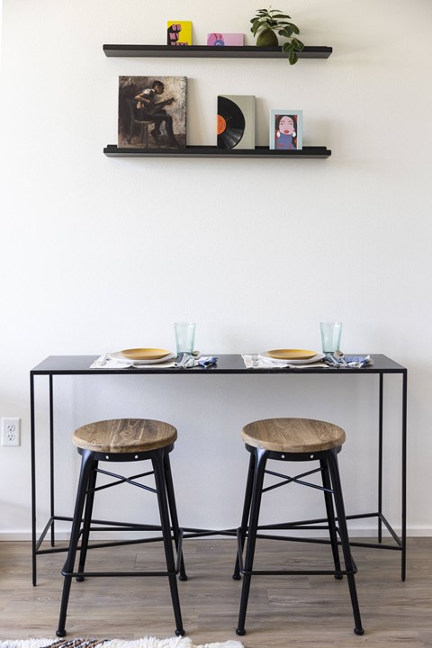 a kitchen with two stools and a table with a shelf on the wall at Analog PDX Apartments, Portland