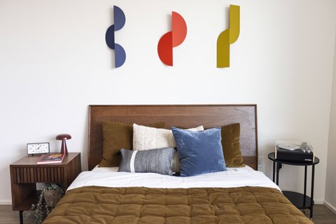 a bedroom with a bed and colorful art on the wall at Analog PDX Apartments, Portland, OR 97227