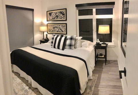 A bedroom with a large bed and two lamps.