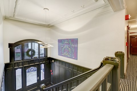 A staircase with a green railing and a purple painting on the wall at Clay & Tiffany, Portland, 97201