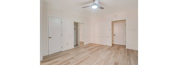 A room with wooden floors and white walls, with a ceiling fan and three doors at Clay & Tiffany, Portland, 97201
