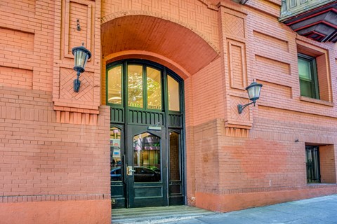A red brick building with a black door and two lamps on either side.
