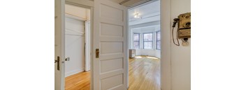 A white door with a brass handle is open to a room with wooden floors and a window at Clay & Tiffany, Portland, 97201