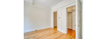 A room with white walls and wooden floors with two doors.