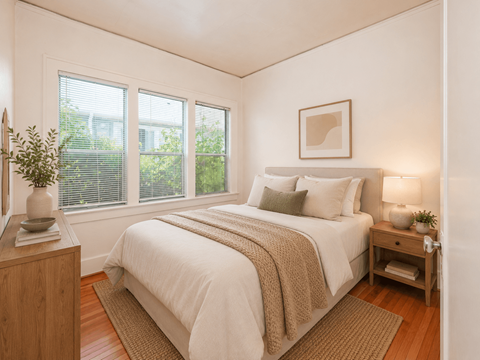 A bedroom with a bed, nightstand, and window.