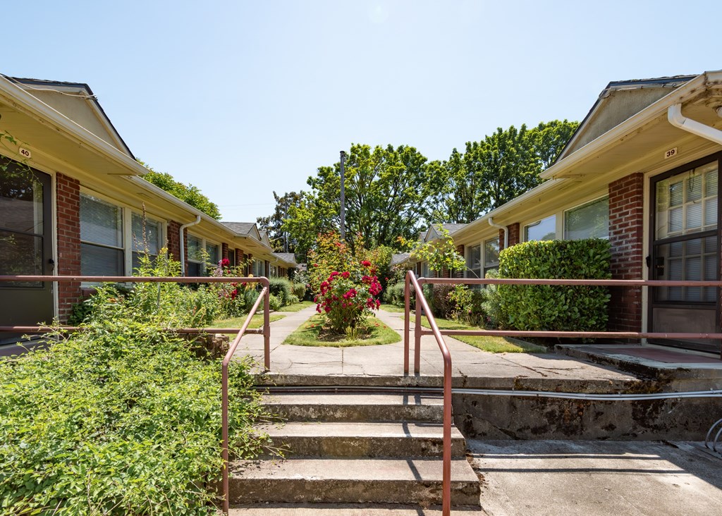 A row of houses with a red metal railing in front of them.