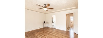 A room with a ceiling fan and wooden floors.