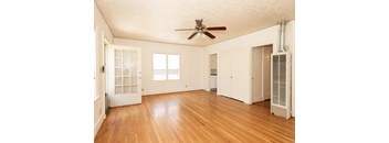 A room with a ceiling fan and wood flooring.