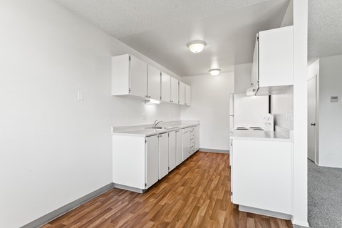 A kitchen with white cabinets and wooden floors.