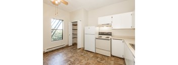 A kitchen with white appliances and brown tiled floors.