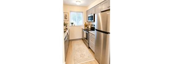 A kitchen with a stainless steel refrigerator and wooden flooring.