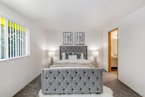 A bedroom with a large bed and two lamps.
