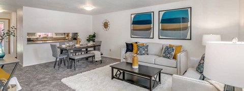 A living room with a white couch, a coffee table, and a dining table with chairs.
