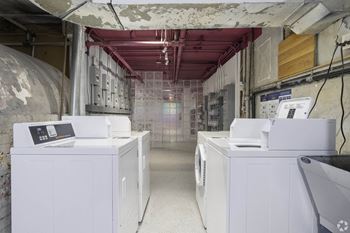 a laundromat with four washing machines in a long room with exposed wiring at Clay & Tiffany, Portland, OR, 97201