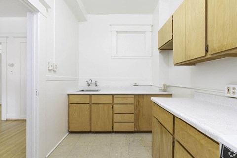 a small kitchen with white walls and wooden cabinets at Clay & Tiffany, Portland, OR, 97201