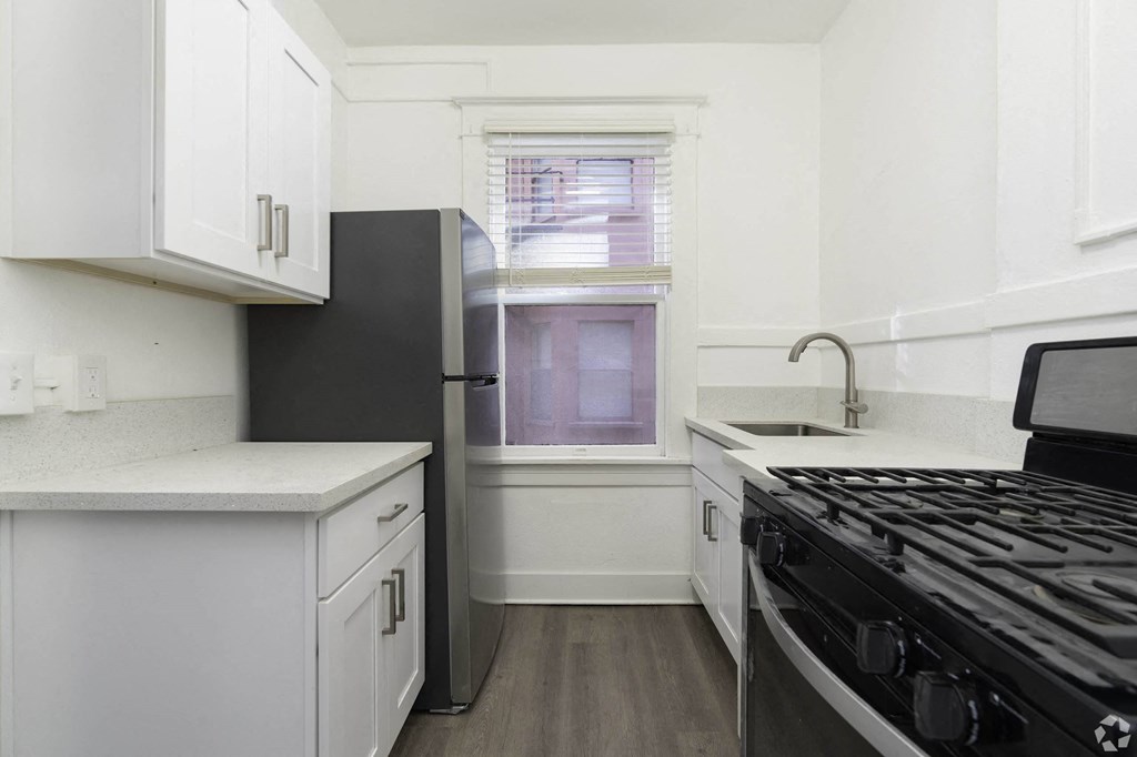 a kitchen with white cabinets and a stove and a window at Clay & Tiffany, Portland, 97201