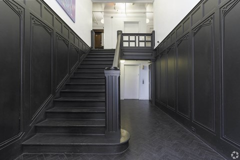 the lobby of a building with a staircase and black doors at Clay & Tiffany, Portland, 97201