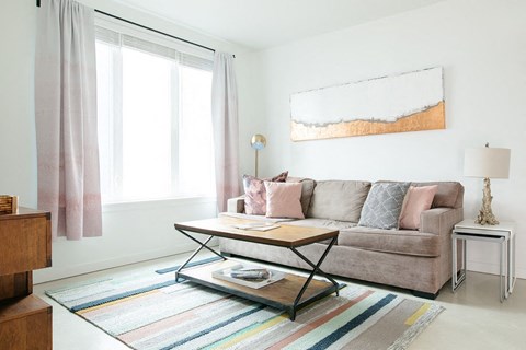 A living room with a couch, a coffee table, and a painting on the wall.