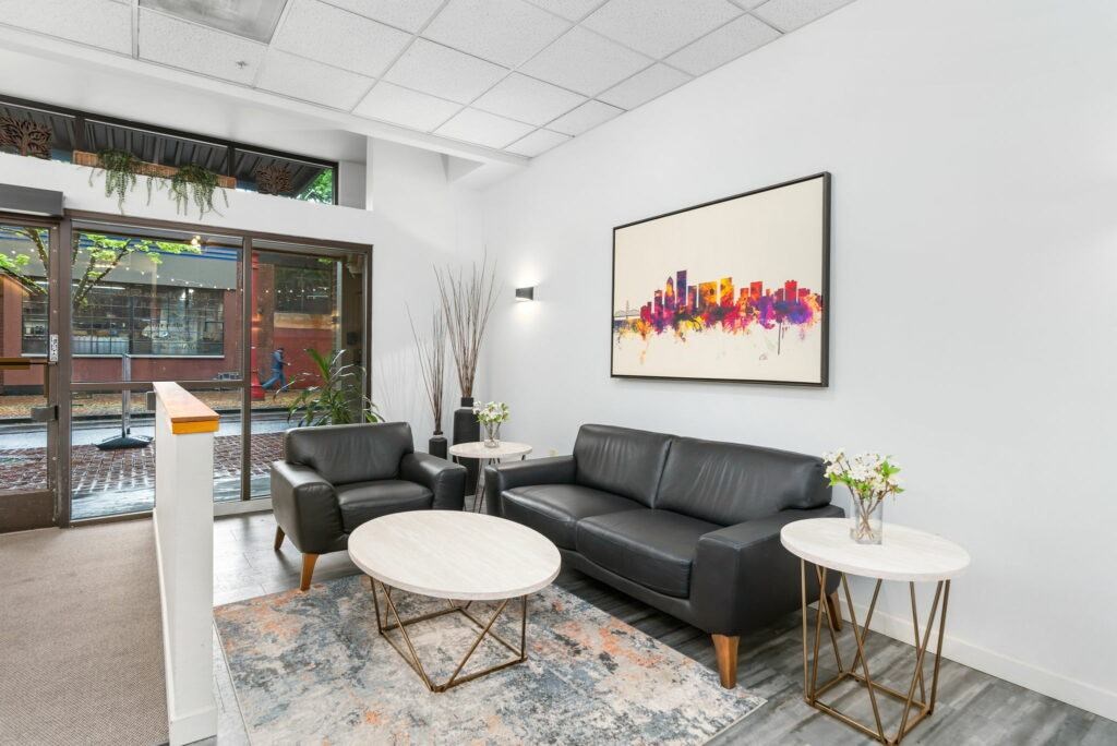 A black leather couch sits in a room with a large picture frame on the wall.at Fifth Avenue Place Apartments, Portland