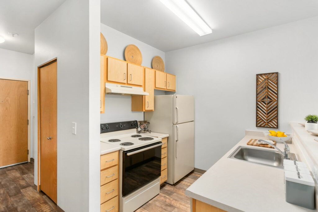 A kitchen with a white counter top and a white refrigerator.at Fifth Avenue Place Apartments, Oregon