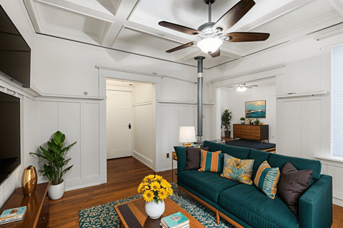 A living room with a green couch and a ceiling fan.