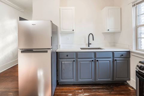 A kitchen with a stainless steel refrigerator and a grey cabinet.