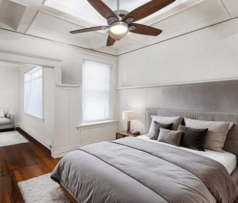 A bedroom with a large bed and a ceiling fan.