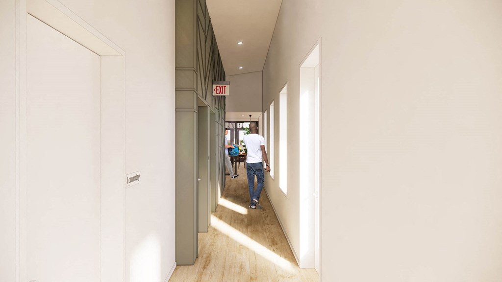 a man walking down a long hallway with white walls and wood floors at Moraine, Tacoma, WA 
