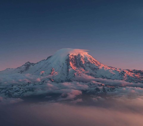 A snow-covered mountain peak rises above the clouds.