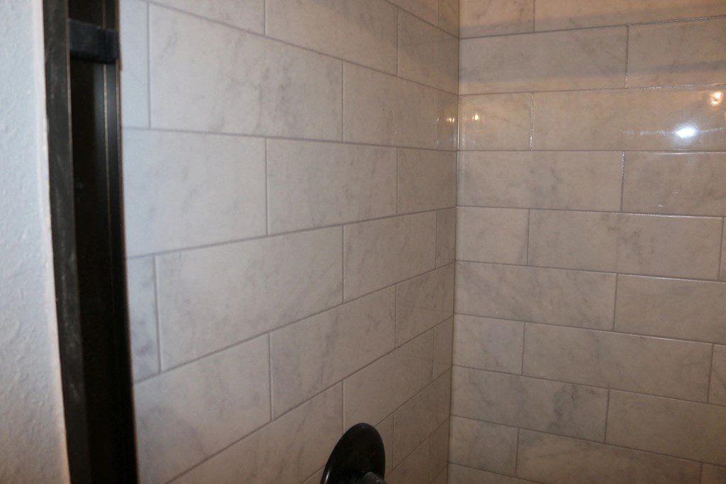 a tiled shower in a bathroom with a person standing in it at Schaefer Ridge Apartments, Branson , MO 65616