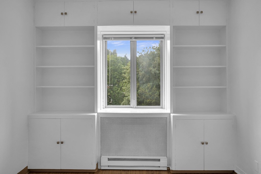 a room with white shelves and a window and a view of trees