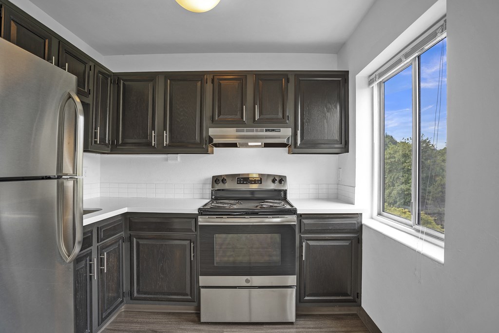 a kitchen with black cabinets and stainless steel appliances and a window