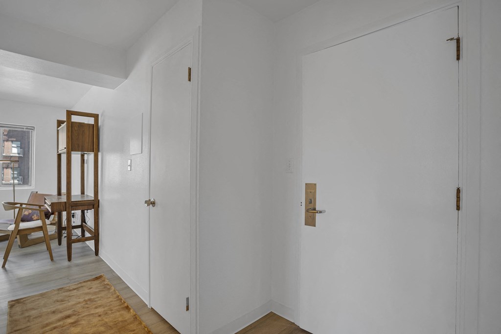 a room with white walls and a white door and a table with a chair