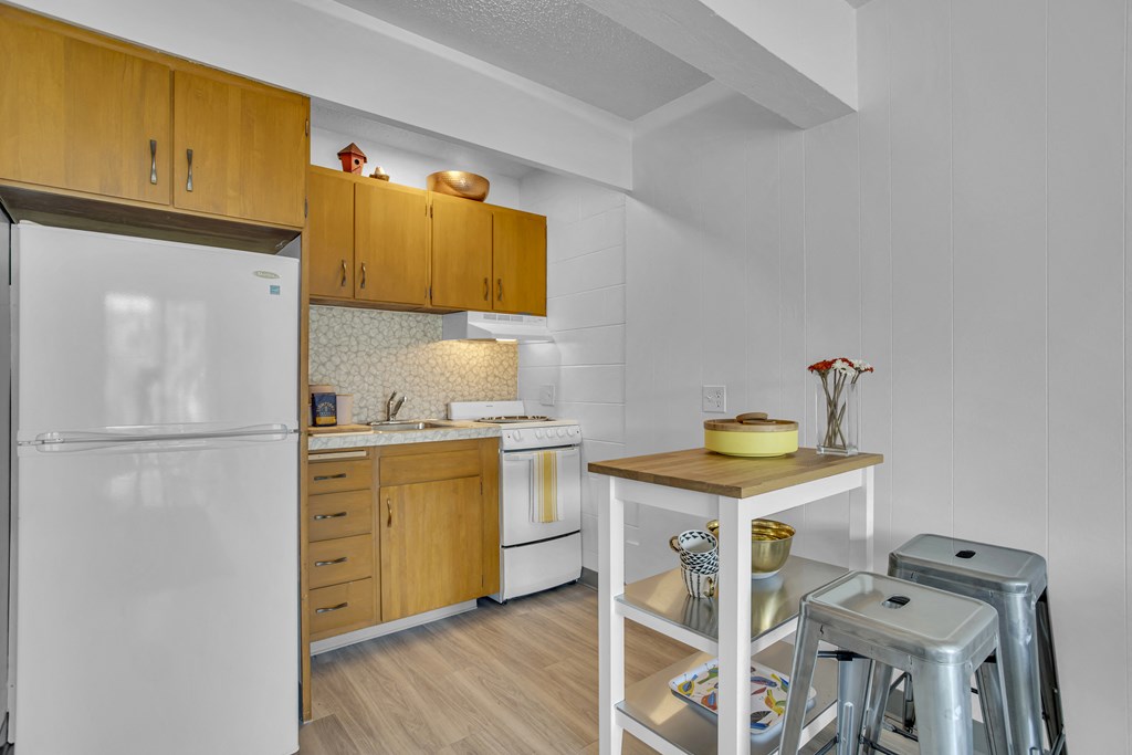 a kitchen with a refrigerator and a counter with stools