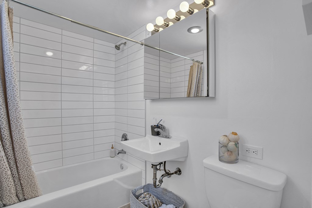 a bathroom with white tiles and a sink and a bath tub