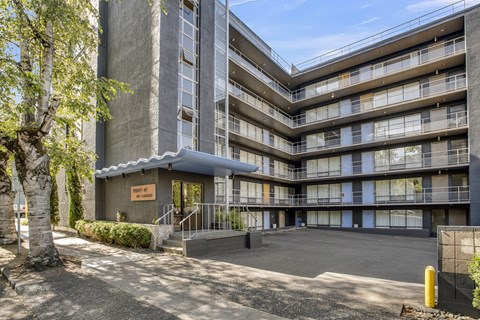 the entrance to an apartment building with a parking lot