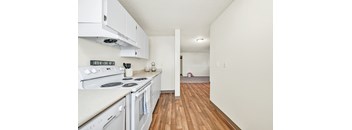 A kitchen with white appliances and wooden floors.
