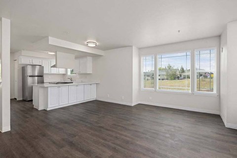 an empty living room and kitchen with a large window
