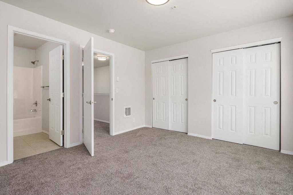 a bedroom with two doors and a bathroom in the background