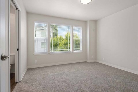 a bedroom with three windows and a door