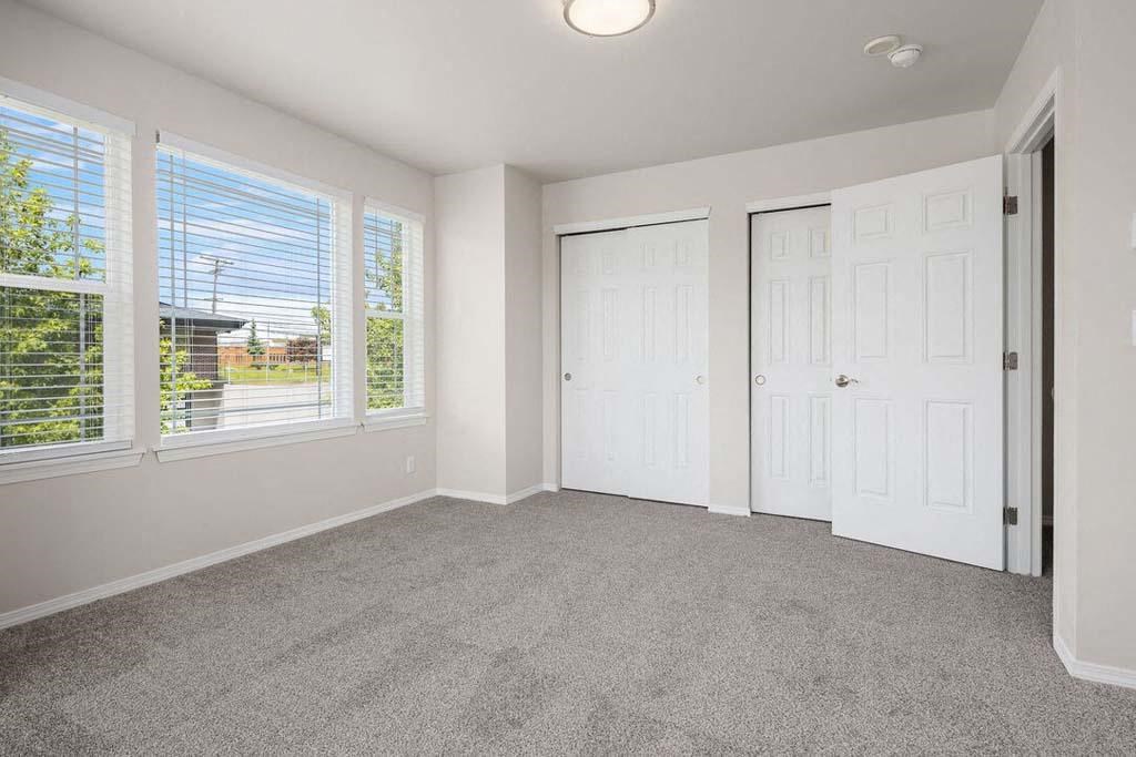 a bedroom with three windows and a door