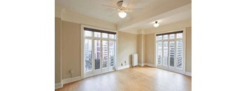 an empty living room with a ceiling fan and french doors