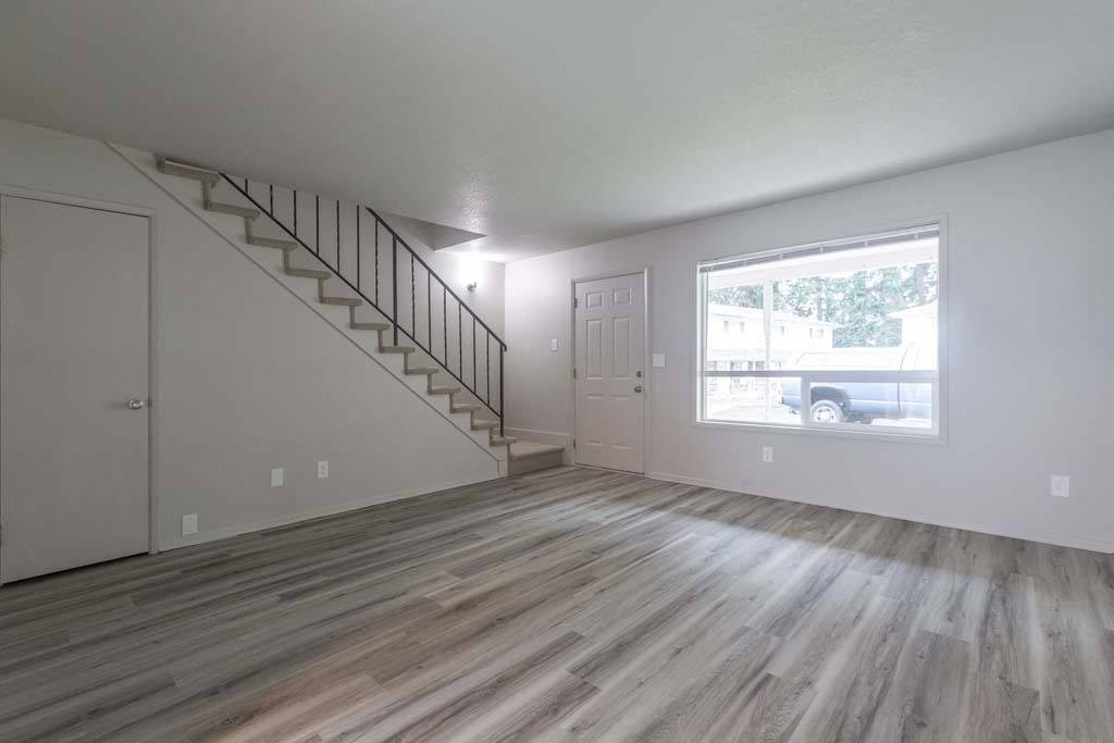 an empty living room with a staircase and a large window