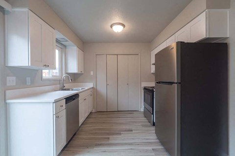 a kitchen with white cabinets and a black refrigerator