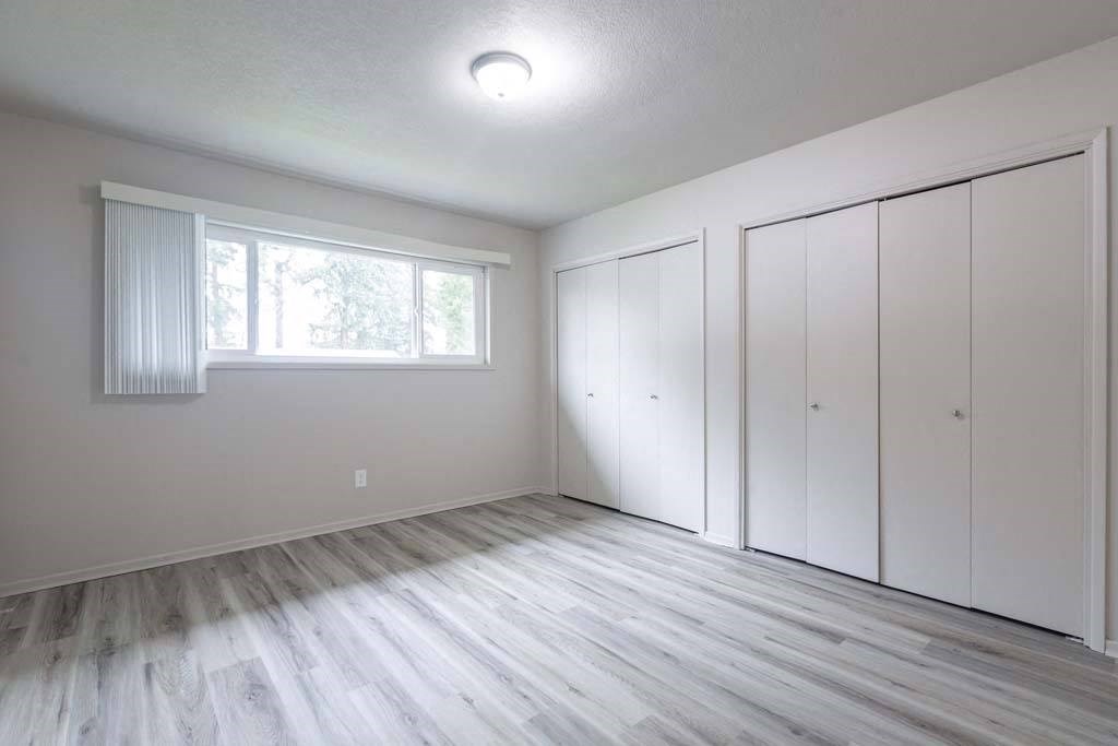 an empty bedroom with a large window and white closets