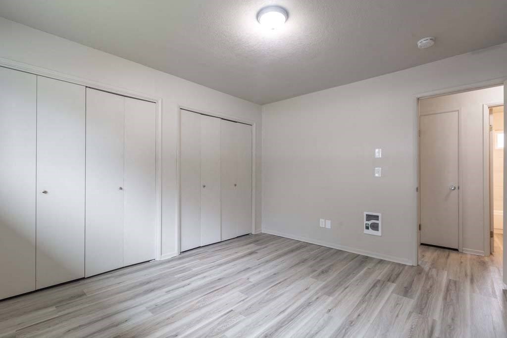 a bedroom with white walls and a wooden floor