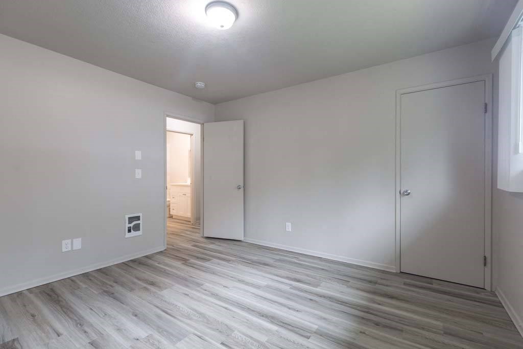a bedroom with hardwood floors and white walls