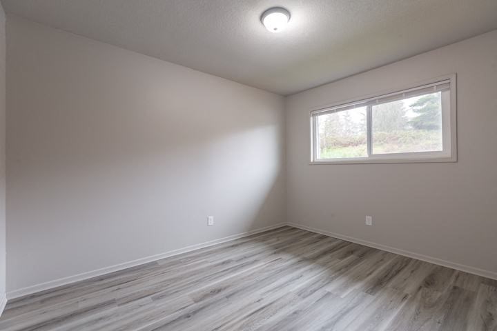 an empty room with a window and wooden floors