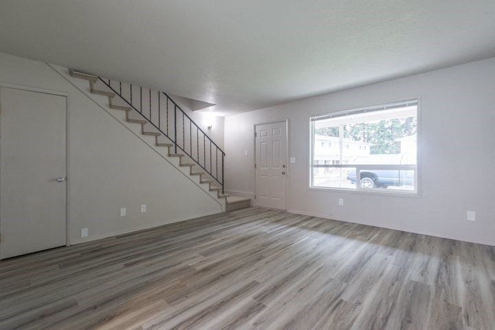 an empty living room with a staircase and a large window