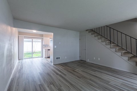 an empty living room with a staircase and a glass door